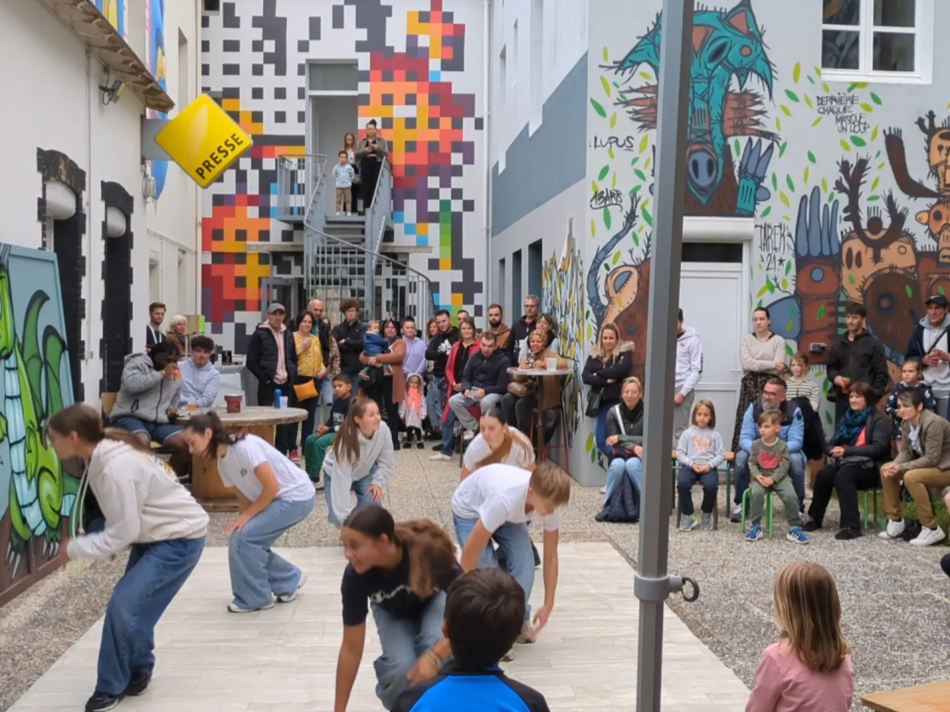 rassemblement de personnes dans la cours de l'association, des jeunes font du hiphop au milieu