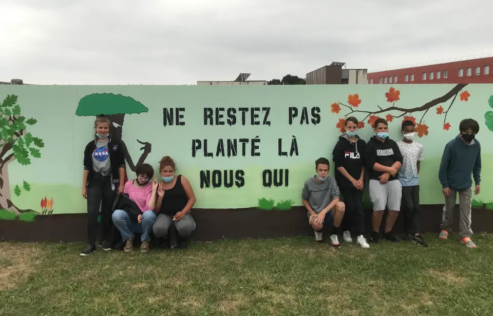 des collegiens autour d'une fresque avec des arbres et inscrit au milieu ne restez pas planté la nous oui
