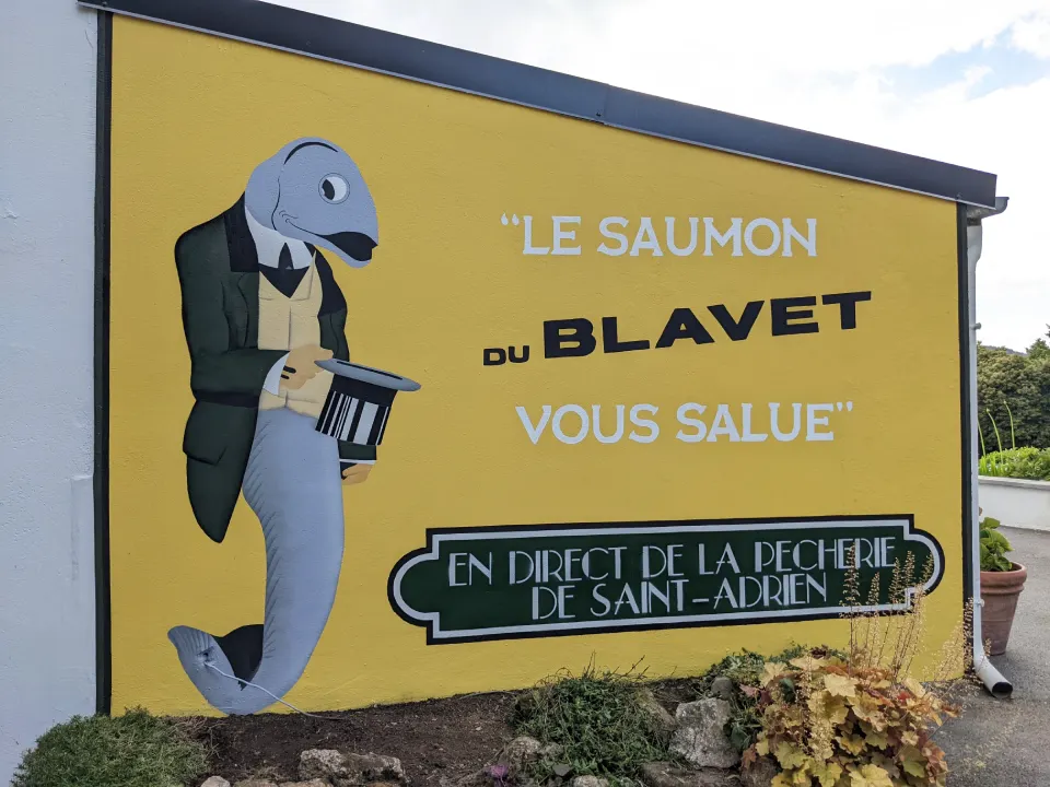 Fresque avec un Somon en costume tenant un chapeau haute forme, il y'a inscrit le saumon du blavet vous salue, en direct de la pecherie de saint-adrien