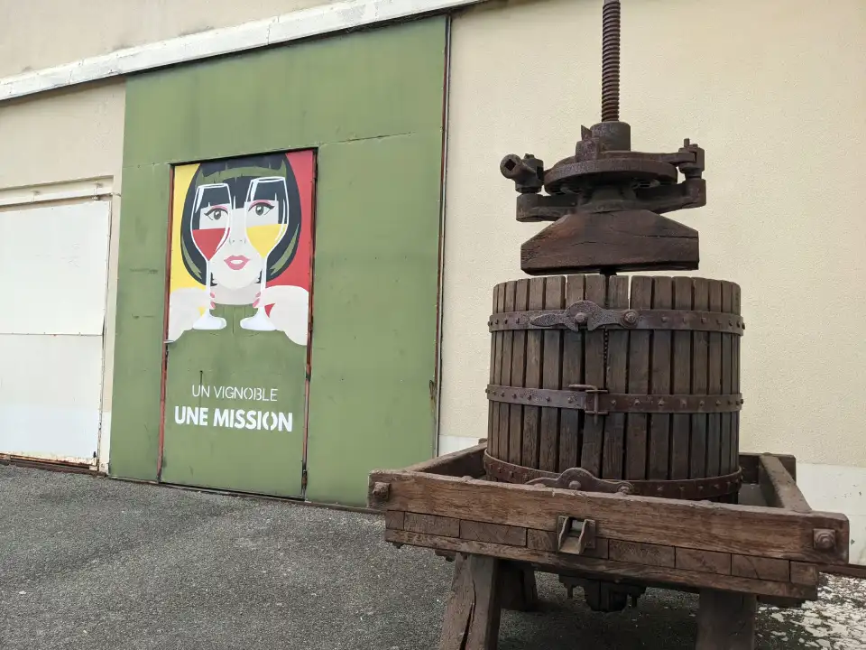 peinture sur une porte d'un batiment avec une femme avec 2 verres de vin devant les yeux et ecris un vignoble une mission