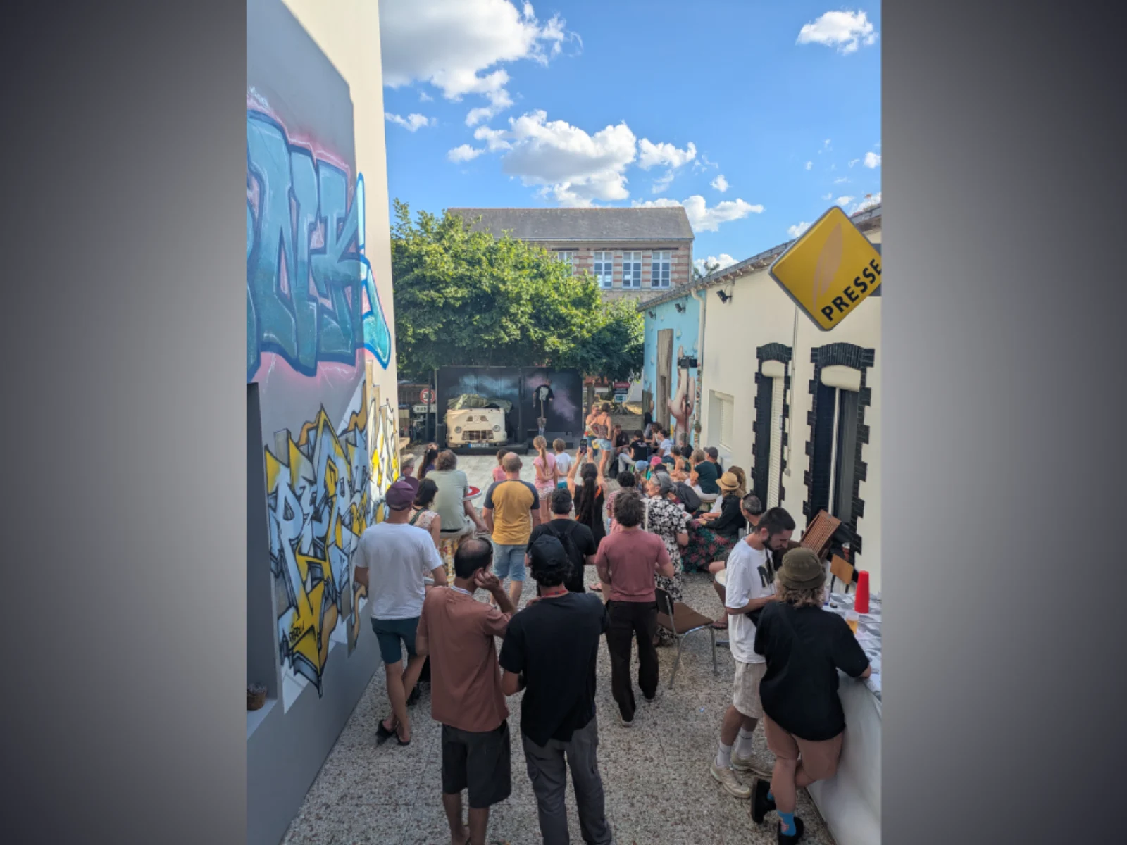 Public lors d’un événement culturel dans les locaux de l’association 13 Arts à Paimboeuf – cour extérieure avec fresques graffiti et ambiance conviviale