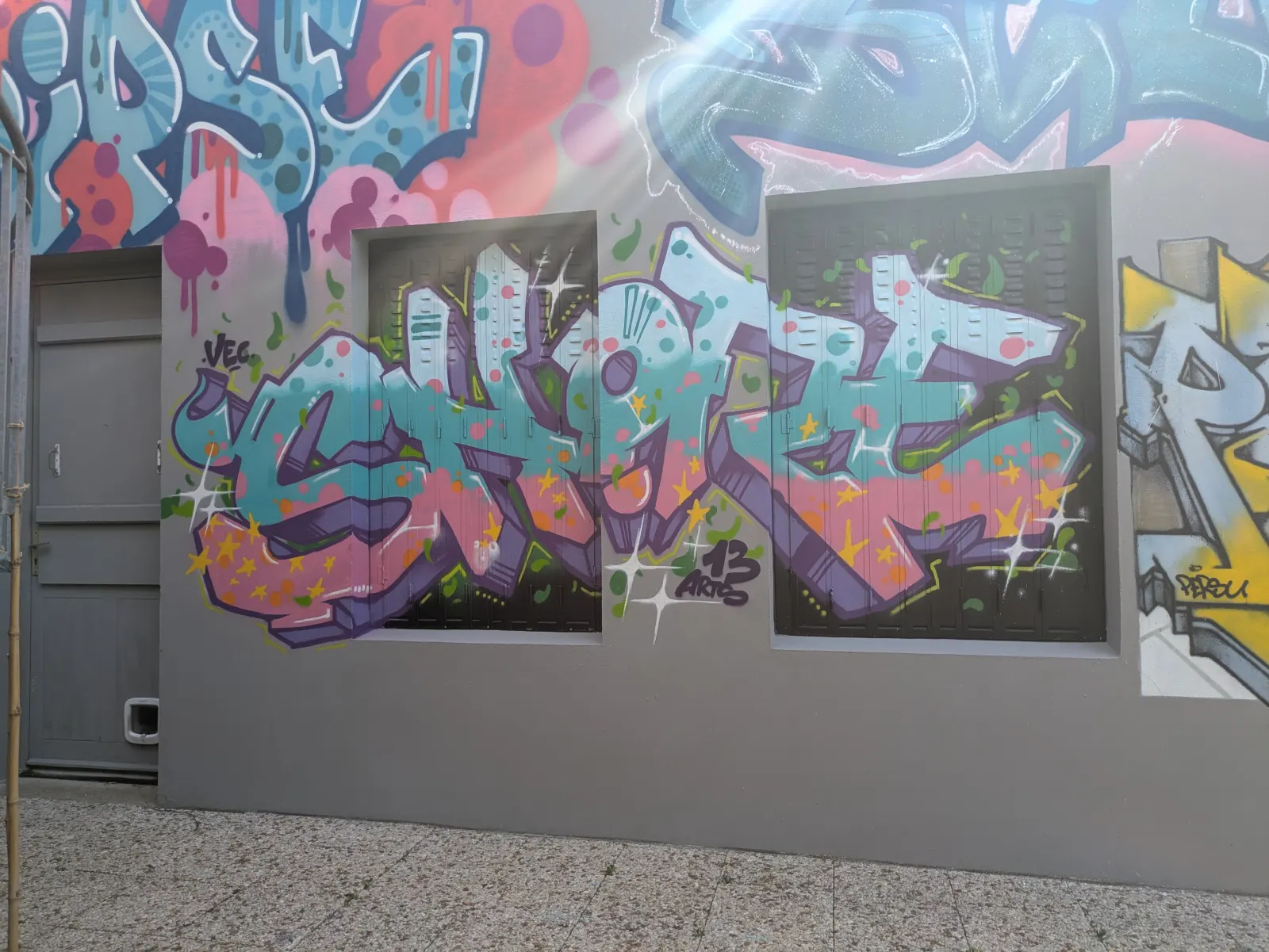 Fresque graffiti colorée réalisée dans les locaux de l’association 13 Arts, lettrage street art sur façade extérieure avec fenêtres et style urbain contemporain