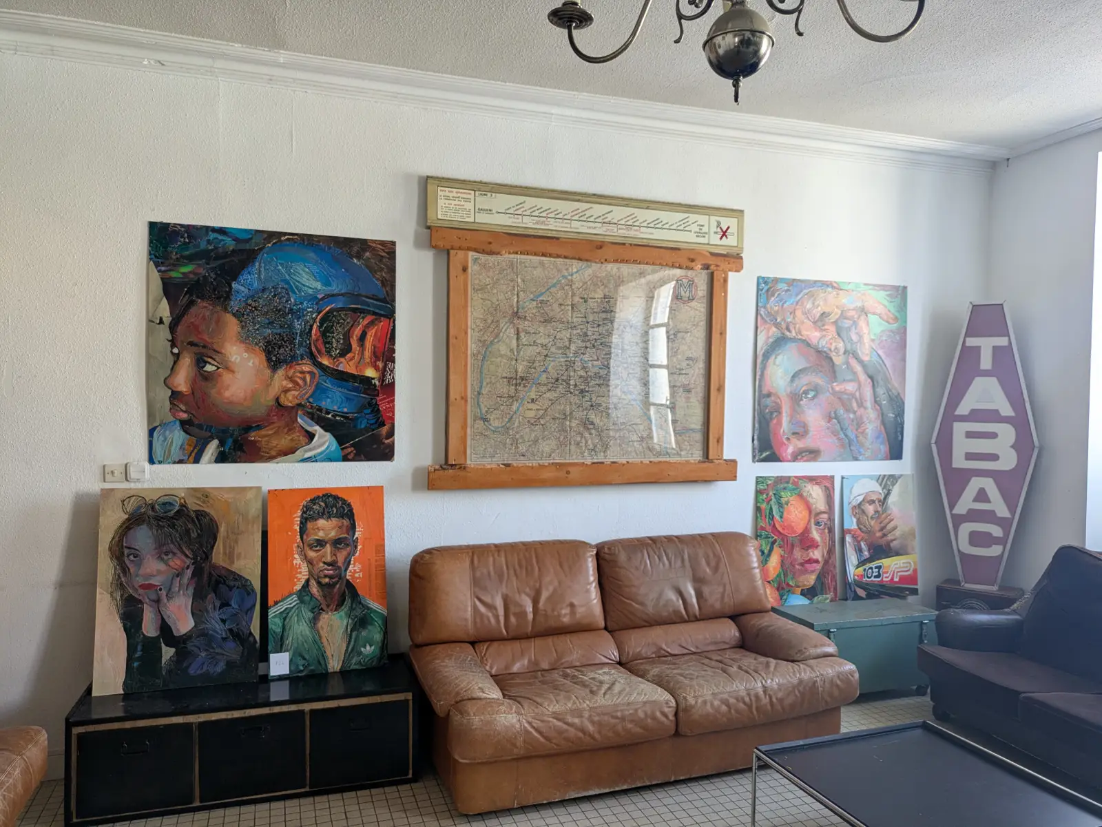 Salle d’exposition des locaux de l’association 13 Arts avec portraits contemporains colorés, canapé en cuir et ambiance artistique